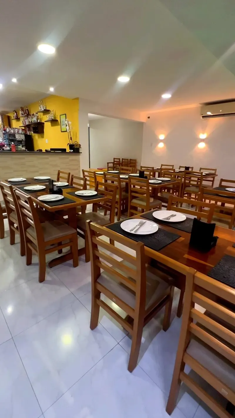 Salão climatizado com mesas de madeira da Pizzaria Primeira Estação
